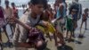 A man shakes a Rohingya Muslim boy while trying to revive him after the boat he was traveling in capsized just before reaching shore at Shah Porir Dwip, Bangladesh, Thursday, Sept. 14, 2017. Nearly three weeks into a mass exodus of Rohingya fleeing violence in Myanmar, thousands were still flooding across the border Thursday in search of help and safety in teeming refugee settlements in Bangladesh. 