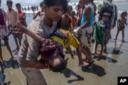 A man shakes a Rohingya Muslim boy while trying to revive him after the boat he was traveling in capsized just before reaching shore at Shah Porir Dwip, Bangladesh, Thursday, Sept. 14, 2017.