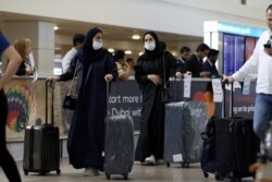 Travelers wear masks as they arrive at the Dubai International Airport