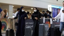 Travelers wear masks as they arrive at the Dubai International Airport