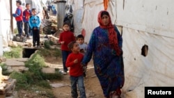 FILE - Syrian refugees walk in an informal settlement in Zahle in the Bekaa Valley, Lebanon, Oct. 16, 2014. 