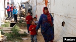 Syrian refugees walk in an informal settlement in Zahle in the Bekaa Valley, Lebanon, Oct. 16, 2014. 