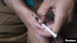 FILE - A man injects himself with heroin using a needle obtained from the People's Harm Reduction Alliance, the nation's largest needle-exchange program, in Seattle, Washington. Drugs were a leading reason for the rise in premature death rates among young, white Americans.