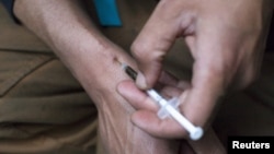 FILE - A man injects himself with heroin using a needle obtained from the People's Harm Reduction Alliance, the nation's largest needle-exchange program, in Seattle, Washington. 