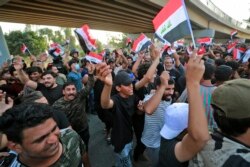 Iraqi protesters lift national flags during a demonstration against last month's election result, near an entrance to the Green Zone in Baghdad, November 5, 2021.