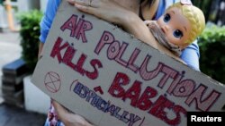 Aktivistkinja za zaštitu životne sredine drži kartonski znak i lutku na protestu u Jakarti u Indoneziji, 16. septembra 2021. (Foto: Reuters/Willy Kurniawan)