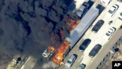 In this frame from video provided by KNBC television in Los Angeles, smoke rises from vehicles as a fast-moving wildfire swept across Interstate Highway 15 near Hesperia, Calif., July 17, 2015.