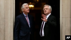 FILE - The European Commission's chief negotiator for the U.K. exit from the European Union, Michel Barnier, left, and David Davis, Britain's secretary of state for exiting the European Union, pause ahead of a meeting at 10 Downing Street, London, Feb. 5, 2018.