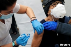 A health care worker administers a shot of the Moderna COVID-19 vaccine to a woman at a pop-up vaccination site operated by SOMOS Community Care during the COVID-19 pandemic in New York City on Jan. 29, 2021.