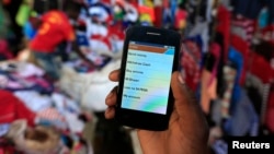 A man holds up his mobile phone showing an M-Pesa mobile money transaction page at an open-air market in Kibera in Kenya's capital, Nairobi, Dec. 31, 2014.