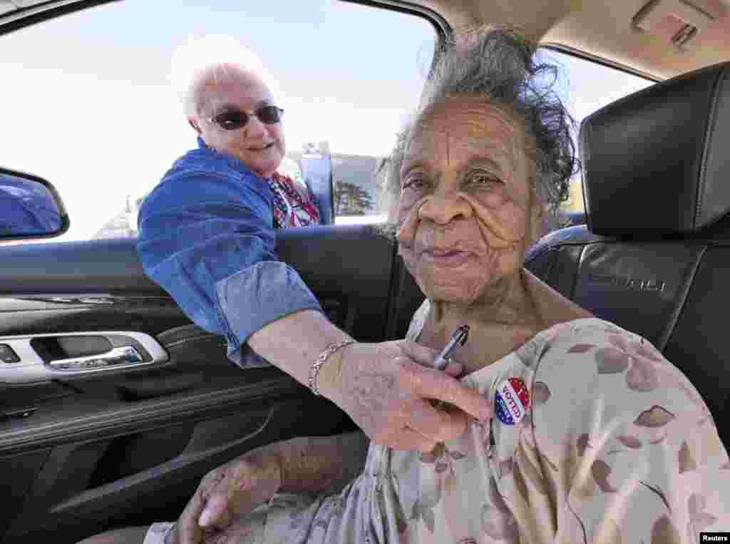 Grace Bell Hardison, a 100-year-old woman, receives an &quot;I Voted Today&quot; sticker from election official Elaine Hudnell after she cast her ballot from a car in Belhaven, North Carolina. President Barack Obama recently mentioned her after attempts were made to purge her from the voter registration list and hence deny her right to vote.