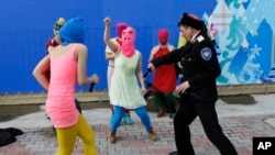 Members of the punk group Pussy Riot, including Nadezhda Tolokonnikova in the blue balaclava and Maria Alekhina in the pink balaclava, are attacked by Cossack militia in Sochi, Russia, on Feb. 19, 2014. 