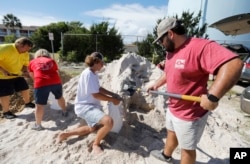 South Carolina Walker Townsend, at right, from the Isle of Palms, S.C., fills a sand bag while Dalton Trout, in center, holds the bag at the Isle of Palms municipal lot where the city was giving away free sand in preparation for Hurricane Florence at the Isle of Palms S.C., Sept. 10, 2018.