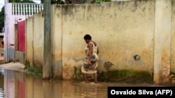 Uma moradora caminha pela água nas ruas inundadas do Futungo, Luanda, a 20 de Abril de 2021