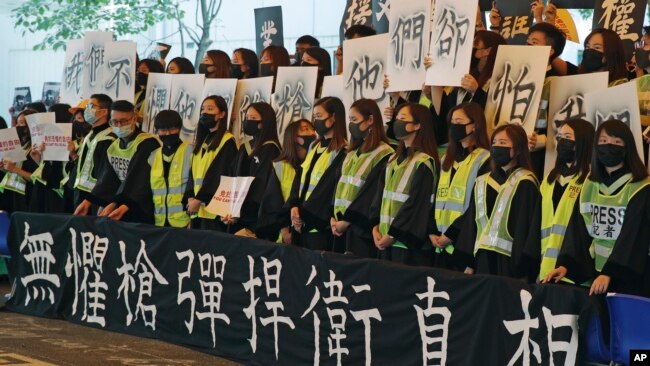 香港中文大学毕业生在2019年11月7日的毕业典礼上戴口罩手举标语横幅抗议。