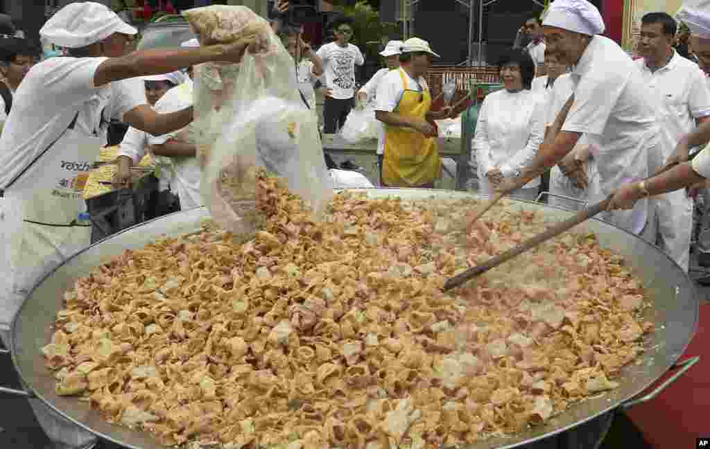 Thai chefs cook vegetarian food from a giant cooking bowl during the vegetarian festival celebration in Chiang Mai province, northern Thailand.