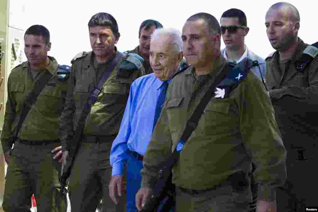 Israel's President Shimon Peres (center) walks with Israeli military commanders during a visit to the site of an Iron Dome anti-missile shield, near the southern city of Ashkelon, July 17, 2014.