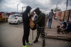 An Indian paramilitary soldier checks the bag of a Kashmiri man at a busy market in Srinagar, Indian-controlled Kashmir, Oct. 11, 2021.