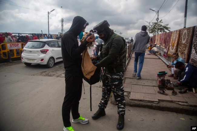 An Indian paramilitary soldier checks the bag of a Kashmiri man at a busy market in Srinagar, Indian-controlled Kashmir, Oct. 11, 2021.