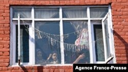 FILE - A family watches from a window as people carry the body of a local Pandit businessman killed by suspected anti-Indian gunmen a day before, during his funeral in Srinagar, Indian-administered Kashmir, Oct. 6, 2021. 