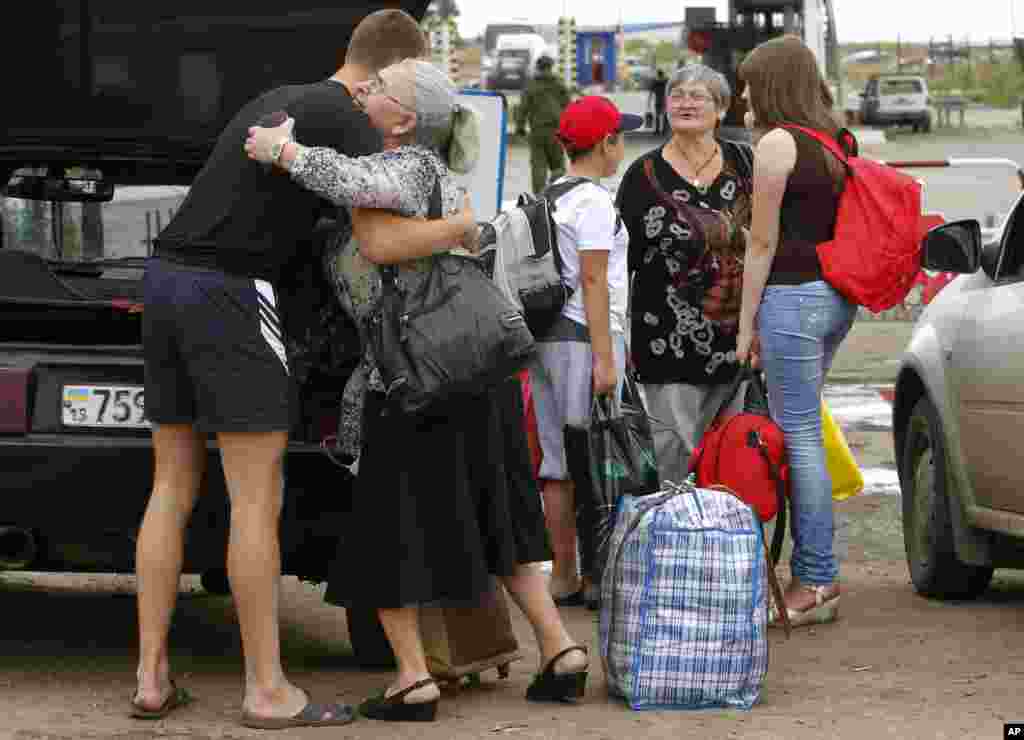 A man says goodbye to his relatives as they prepare to cross the border into Russia at the checkpoint in Izvaryne, Luhansk region, eastern Ukraine, June 26, 2014. 