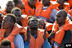 FILE - Migrants and refugees seated on a rubber boat wait to be rescued by the Topaz Responder, a rescue ship run by Maltese NGO "Moas" and the Italian Red Cross, Nov. 4, 2016 off the Libyan coast.