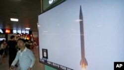 Warga di Seoul melewati layar televisi yang memperlihatkan liputan mengenai peluncuran roket Korea Utara, Agustus 2016.
