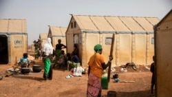 FILE - Displaced women prepare food at Kaya Camp, 100 km north of Ouagadougou, Burkina Faso, Feb. 8, 2021.