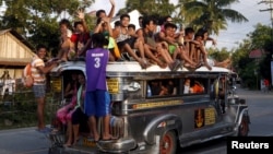 FILE - Residents ride on top of an overcrowded "jeepney", a locally manufactured public transport, along a highway in Mogpog town on Marinduque island in central Philippines, April 8, 2015. 