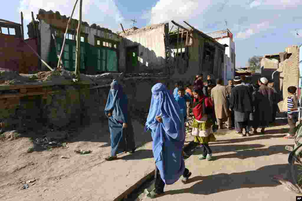 Afghan women walk towards a damaged house following an earthquake, in Kabul, Afghanistan, Oct. 26, 2015.
