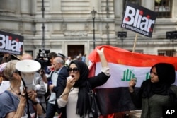 A British Iraqi protester holds up an Iraqi flag, during a protest, outside the Queen Elizabeth II Conference Centre in London, after the publication of the Chilcot report into the Iraq war, July 6, 2016.