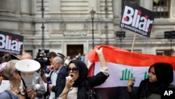 Un manifestant irakien britannique brandit un drapeau irakien, lors d'une manifestation, à l'extérieur du centre de conférences Queen Elizabeth II à Londres, 6 juillet 2016. 