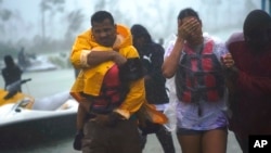A family is escorted to a safe zone after they were rescued as Hurricane Dorian continues to rain in Freeport, Bahamas, Tuesday, Sept. 3, 2019. 
