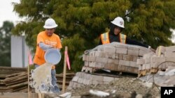 FILE - Workers bucket water from a waterlogged construction site in the Dallas suburb of Richardson, Texas, Oct. 26, 2015. As the flooding from Hurricane Harvey recedes, the rebuilding of Houston may be slowed by a lack of immigrant labor.