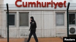 A private security employee stands guard at the entrance of daily newspaper Cumhuriyet's offices, in Istanbul, Jan. 14, 2015. 