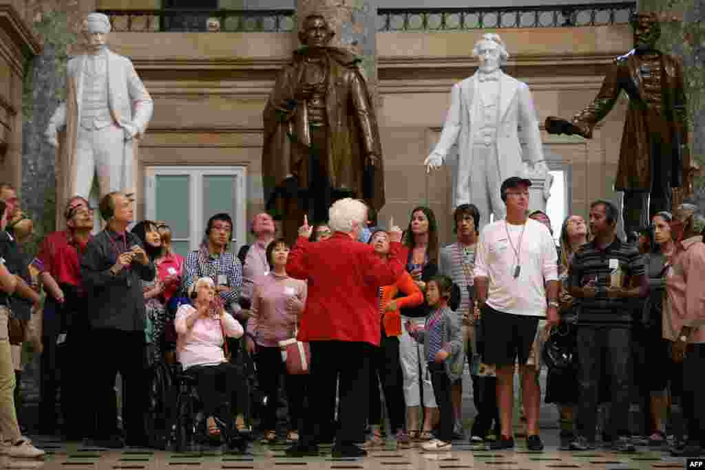 A Capitol Guide Service employee leads a group of tourists through Statuary Hall at the U.S. Capitol in Washington, DC. If Congressional Republicans and Democrats do not find common ground with President Obama on the federal budget then at midnight large sections of the government will close. Members of the Capitol Guide Service are not considered essential employees and tours would halt with a shutdown.