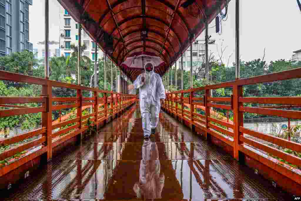 A man wearing protective gear as a preventive measure against the COVID-19 coronavirus walks over a footbridge in Dhaka, Bangladesh.