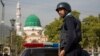 FILE - A Pakistani police officer stands guard outside the Barri Imam shrine in interior Sindh, Islamabad, Pakistan, Feb. 17, 2017.