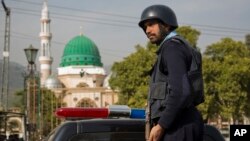 FILE - A Pakistani police officer stands guard outside the Barri Imam shrine in interior Sindh, Islamabad, Pakistan, Feb. 17, 2017.