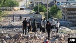 People gather amidst the rubble and damaged vehicles following reported air strikes by the Syrian regime ally Russia, in the town of Kafranbel in the rebel-held part of the Syrian Idlib province on May 20, 2019. 