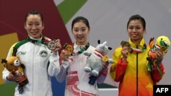 Qi Xinyi dari China (tengah), meraih medali emas wushu untuk nomor changquan putri, bersama peraih medali perak Li Yi (kiri) dari Macau dan peraih medali perunggu, Hoang Thi Phuong Giang dari Vietnam, 22 Agustus 2018.
