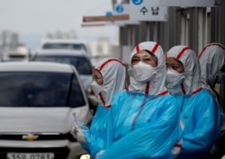 身穿防護服的韓國醫護人員在一個檢查站對開車通過的人進行新冠病毒感染檢測。（2020年3月3日）