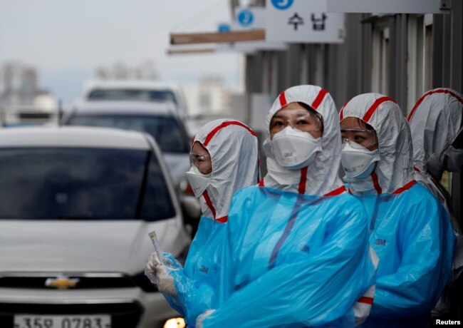 身穿防护服的韩国医护人员在一个检查站对开车通过的人进行新冠病毒感染检测。(2020年3月3日)