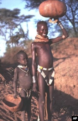 Nyangatom girl with little sister carrying her calabash after watering the family herd. Kibish, Lower Omo, Ethiopia.