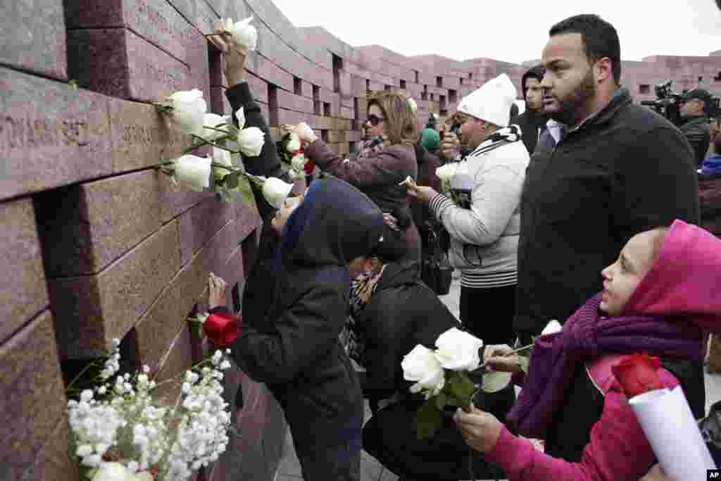 Juan Reyes, right, watches as his nephew, Jason, 9, left, and niece, Yaxiara, 7, lower right, place flowers in a memorial wall in a ceremony marking the 14th anniversary of the crash of American Airlines Flight 587 in the Queens borough of New York. The flight was bound from John F. Kennedy International Airport for the Dominican Republic when it crashed due to mechanical failure shortly after takeoff, killing 260 on board and five on the ground.