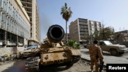 A member of the Libyan pro-government forces, backed by locals, stands near a tank in Benghazi, Libya, Jan. 21, 2015.