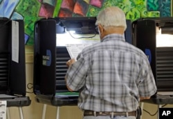 A voter reviews his ballot as he prepares to vote, Aug. 30, 2016, at Precinct 331, in Hialeah, Florida.