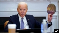 FILE - President Joe Biden holds up a silicon wafer as he participates virtually in the CEO Summit on Semiconductor and Supply Chain Resilience at the White House, April 12, 2021, in Washington. On Jan. 21, 2022, he touted a $20 billion investment by Inte