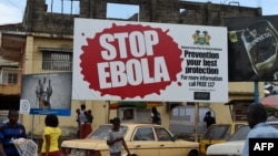 FILES - People walking past a billboard reading "Stop Ebola" in Freetown, Sierra Leone, Nov. 7, 2014. 