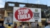 FILE - People walking past a billboard reading "Stop Ebola" in Freetown, Sierra Leone, Nov. 7, 2014. 